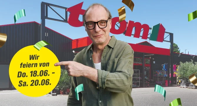 Ein Mensch mit Brille feiert vor einem Baumarkt und zeigt auf ein Datum.