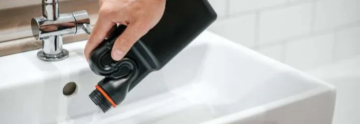 Person gibt Reiniger in Waschbecken