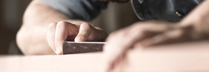 Person schleift Holzplatte