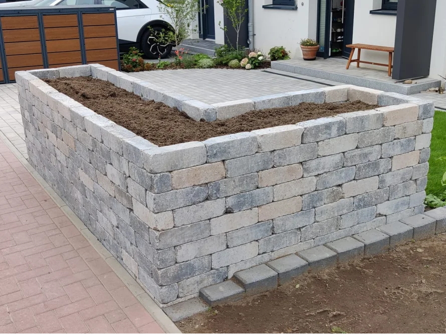 Erhöhtes Blumenbeet aus Pflastersteinen