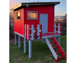 Rotes Gartenhaus auf Stelzen mit grauer Veranda