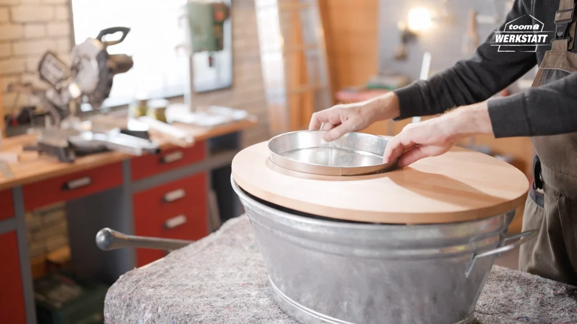 Person setzt Metallring in Holzplatte ein