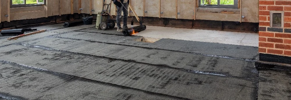 Person bringt Dachpappe mit Gasbrenner an.