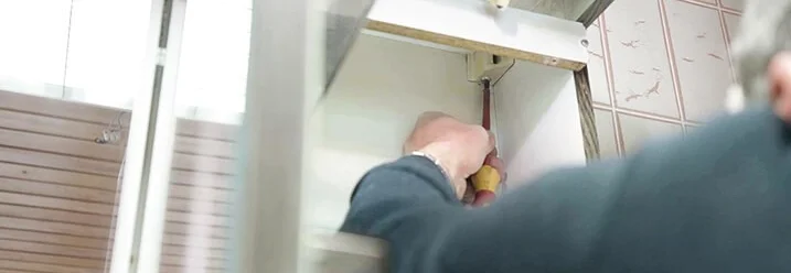 Person montiert Schrank mit Schraubendreher