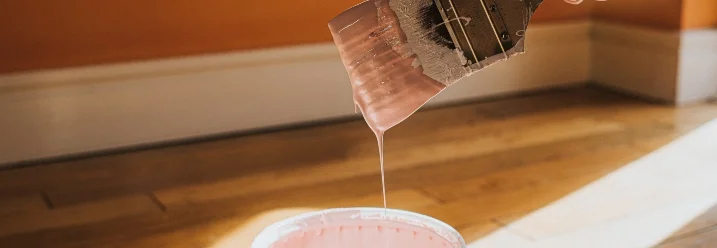 Pinsel mit rosa Farbe über Farbeimer