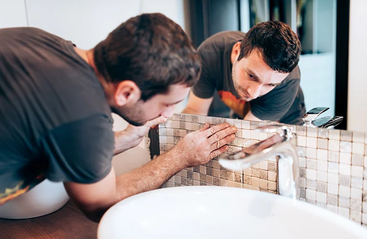 Person bringt Mosaikfliesen an