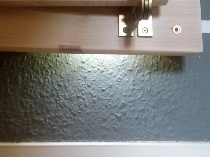 Holzrahmen mit Scharnier über grauer Wand