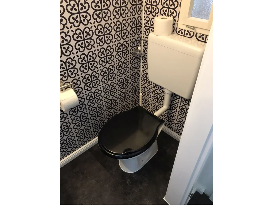 Toilette mit schwarz-weiß gemusterter Wand
