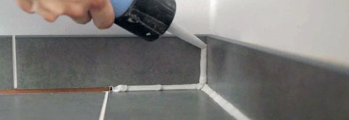 Hand trägt Dichtmittel mit Kartusche auf