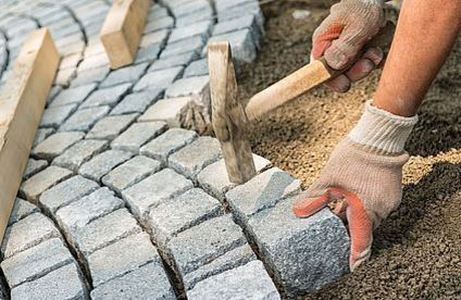 Alternativen zum Betonfundament Mann schlägt Kopfsteine in Boden