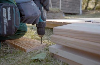 Hochbeet-Maße kalkulieren Ein Handwerke bohrt Löcher in Holzleisten vor.