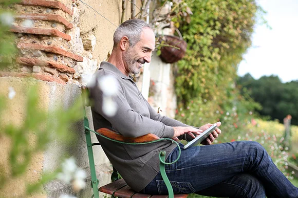 Lächelnde Person benutzt Tablet im Garten