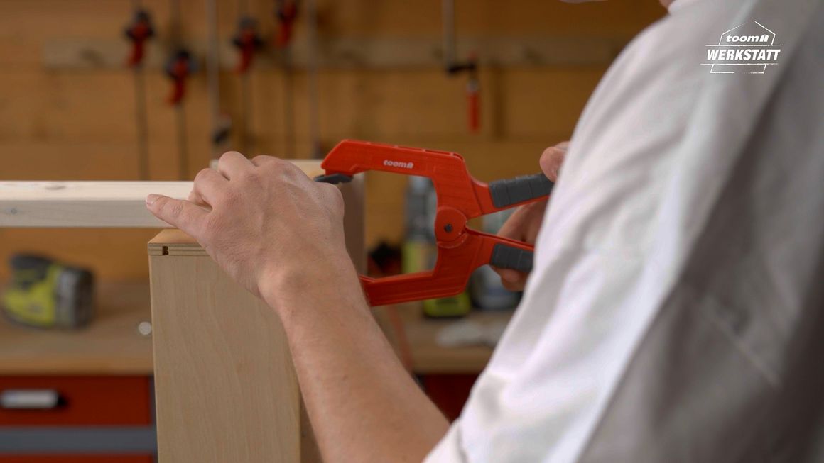 Person befestigt Holz mit Schraubzwinge