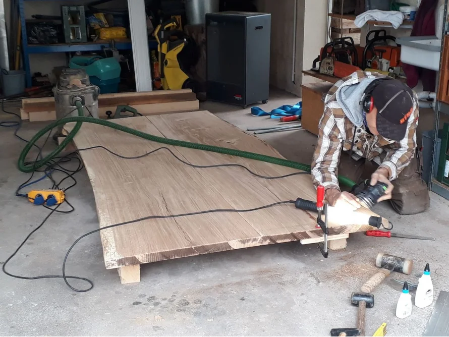 Person schleift Holzplatte in Werkstatt