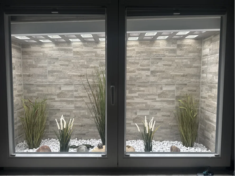 Fensterbank mit Dekogras und Steinen