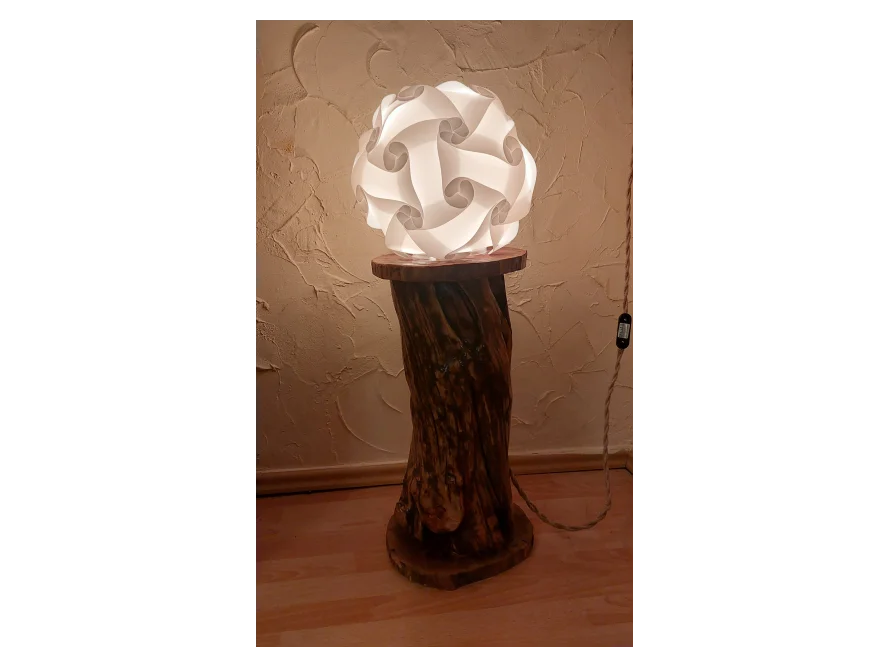 Eine Lampe mit einem Lampenschirm aus Papier auf einem Holzstamm.