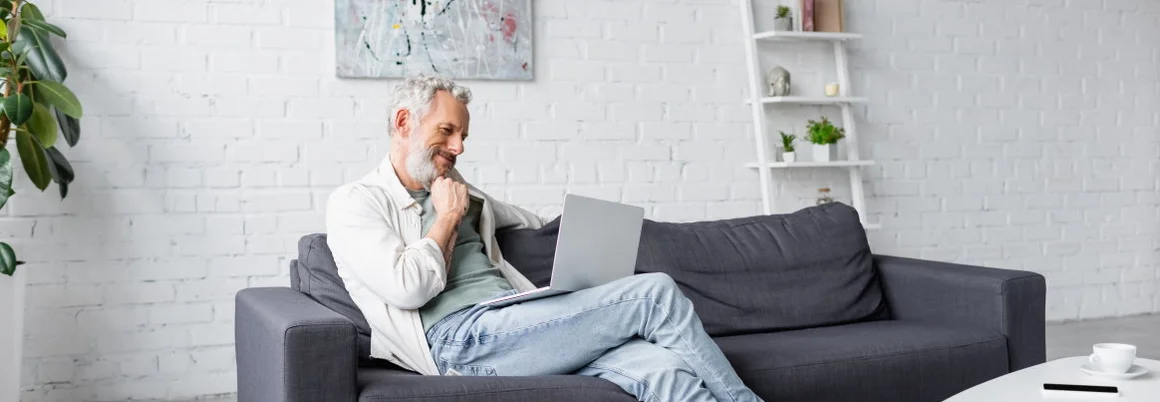 Person mit Laptop auf Sofa