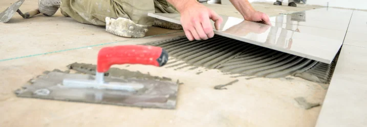 Person verlegt Fliesen mit Zahnspachtel
