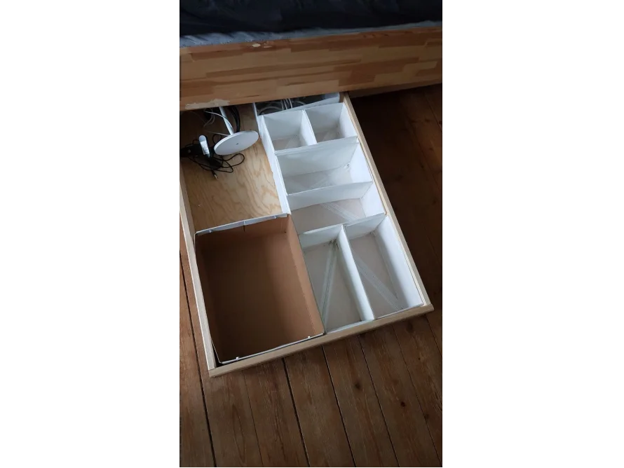 Offene Bettschublade mit Aufbewahrung