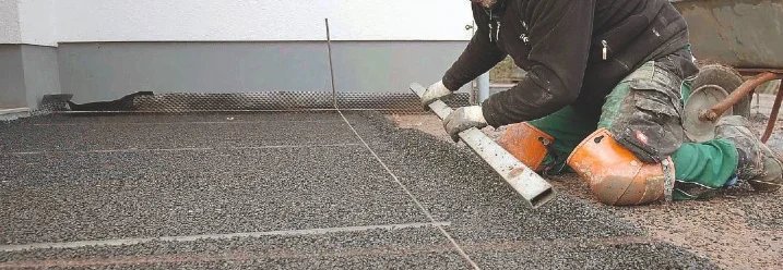 Person ebnet Schotter mit Richtlatte.