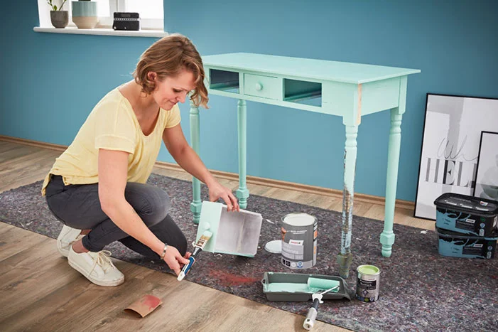 Person streicht einen Holztisch