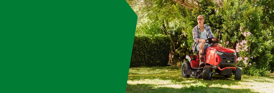 Person mäht den Rasen mit einem roten Rasentraktor.