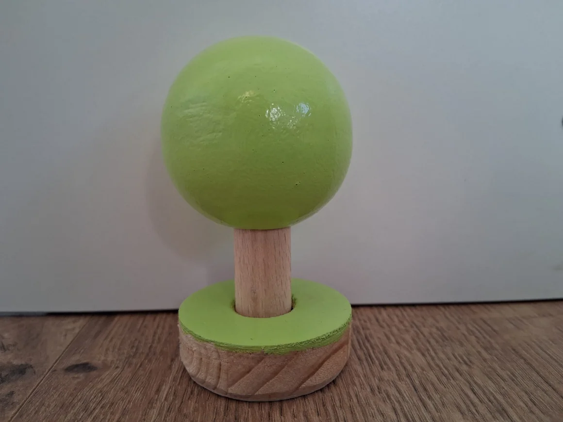 Ein stilisierter Baum aus Holz mit einer runden, grünen Krone.