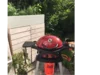 Roter Gasgrill auf Terrasse vor Gartenhaus