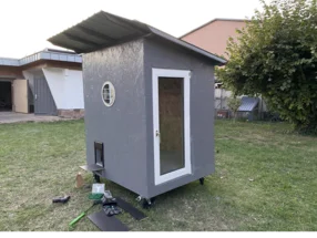 Grau gestrichenes Gartenhaus mit Rädern