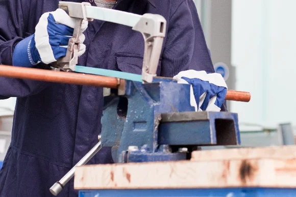 Person sägt mit Bügelsäge ein Rohr.