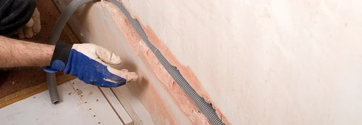 Person verlegt Elektrokabel in Wand