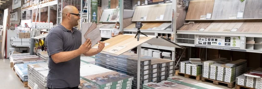 Person präsentiert Bodenbelag in Heimwerkermarkt