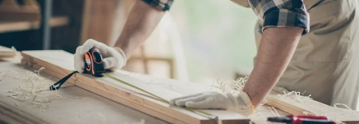 Person misst Holz mit Zollstock ab