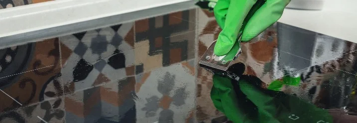 Hand reinigt Ceranfeld mit Schaber