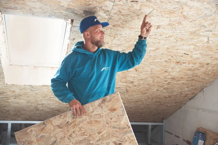 Person beim Verkleiden eines Dachstuhls