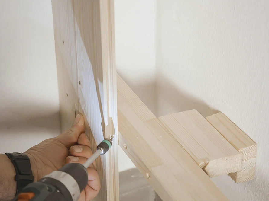 Person verschraubt Holzlatten mit Akkuschrauber.