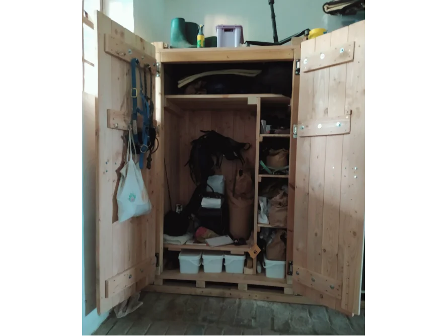 Offener Holzschrank mit Reitausrüstung