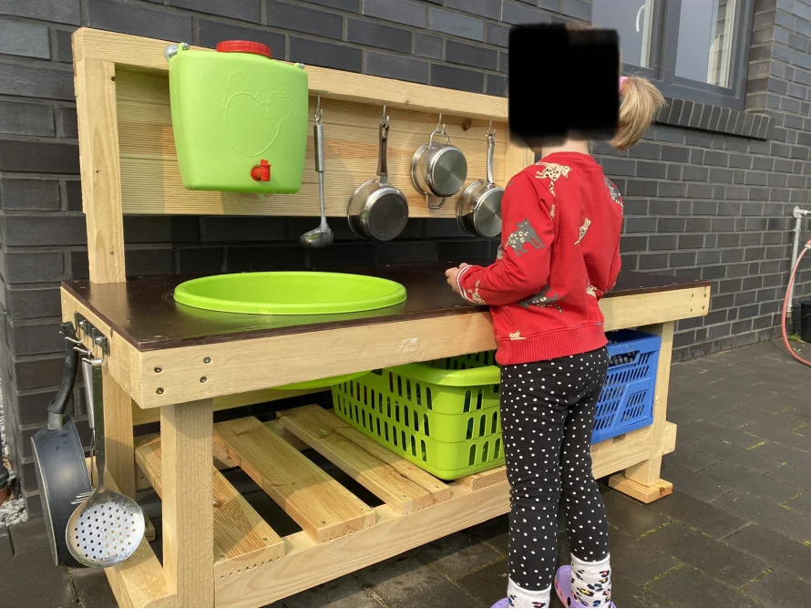 Kind an einer Spielküche aus Holz