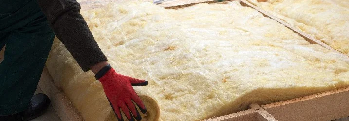 Person dämmt einen Dachboden