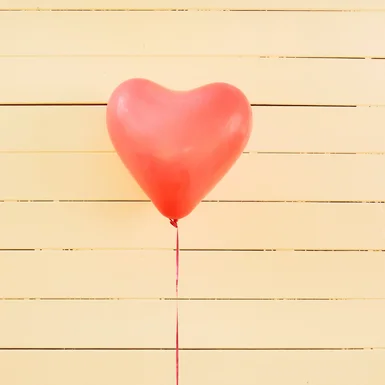 Roter Herzluftballon an Holzwand