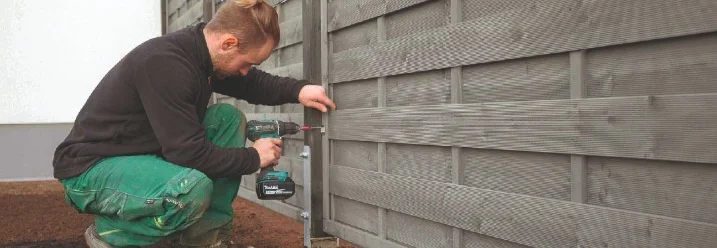 Person baut Holzzaun mit Akkuschrauber