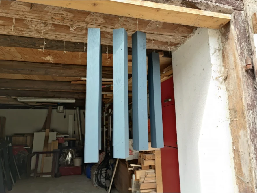 Blau gestrichene Holzbalken hängen zum Trocknen