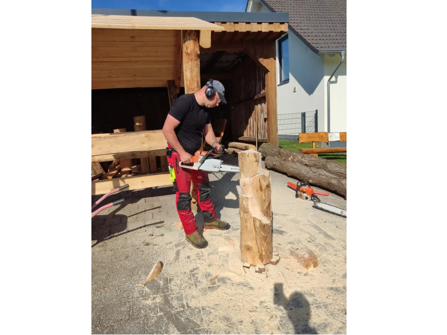 Person schnitzt mit Kettensäge eine Holzskulptur