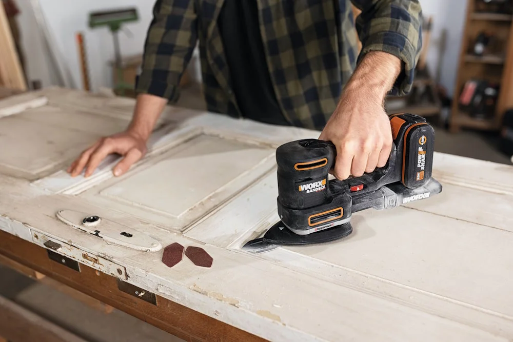 Person schleift Holztür mit Schleifgerät