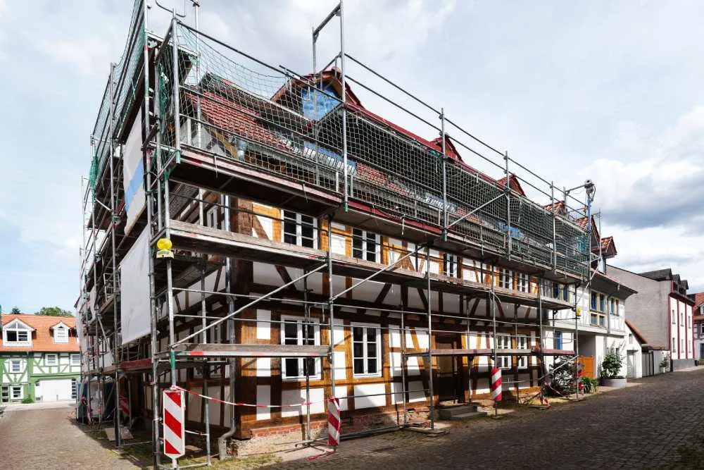 Ein Fachwerkhaus wird mit einem Gerüst saniert.