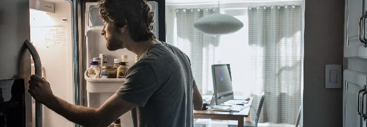 Person schaut in geöffneten Kühlschrank