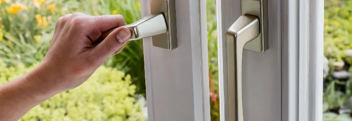 Eine Hand öffnet eine Balkontür.