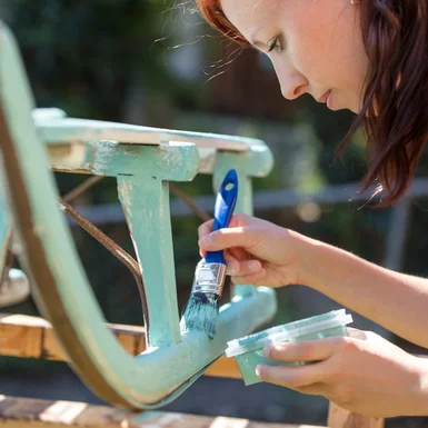 Person streicht einen Schlitten mit Pinsel