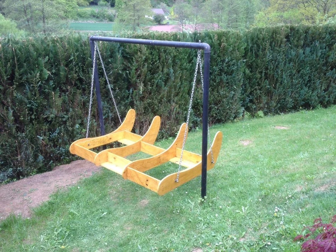 Holzschaukel mit drei Sitzen im Garten