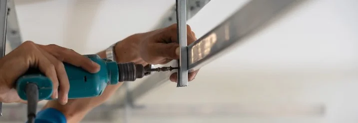 Person montiert eine Metallkonstruktion an der Decke.